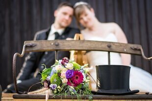 Brautpaar mit Blumenstrauss auf einer Hochzeits-Kutsche.